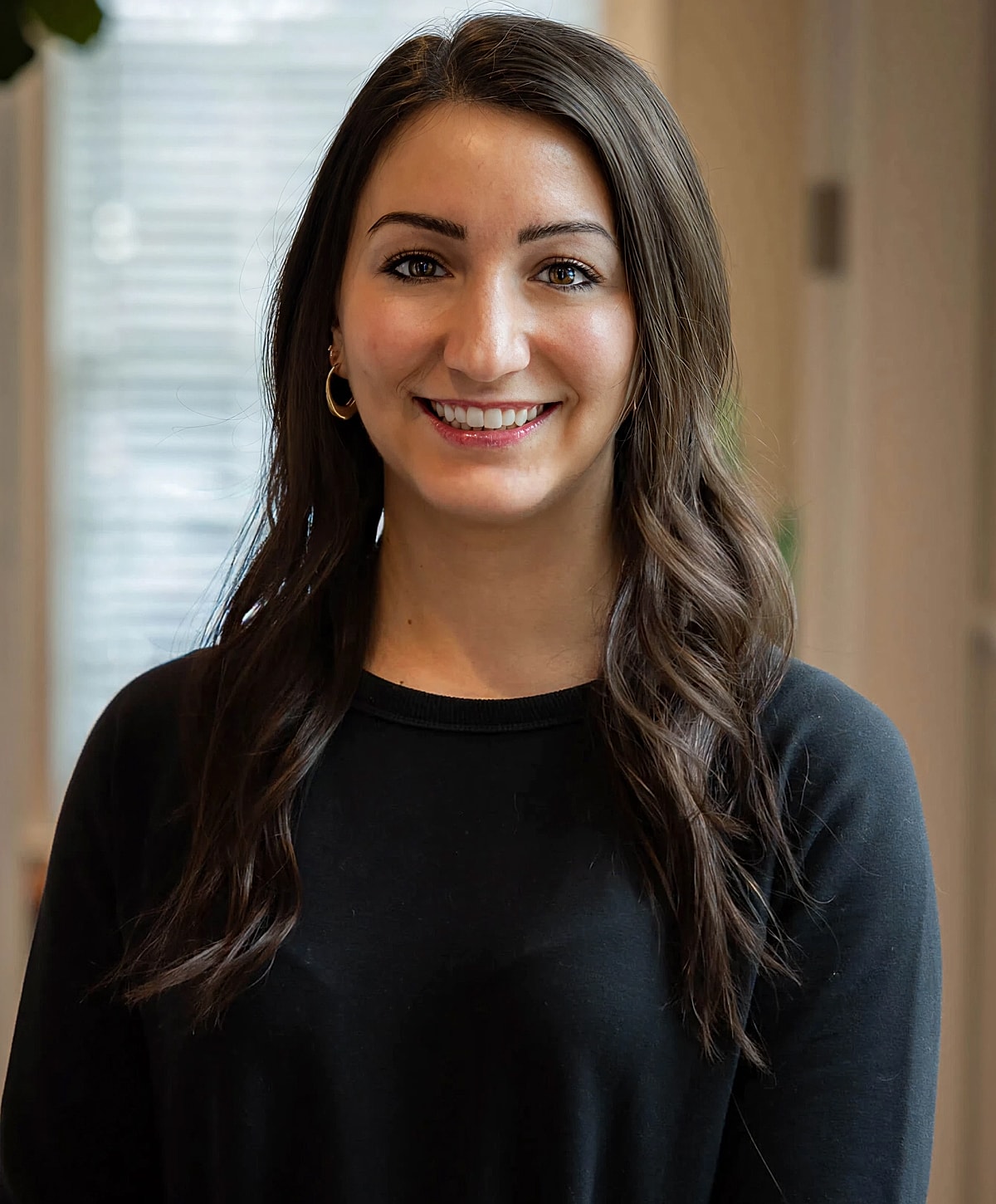 Smiling woman wearing a black sweater indoors.