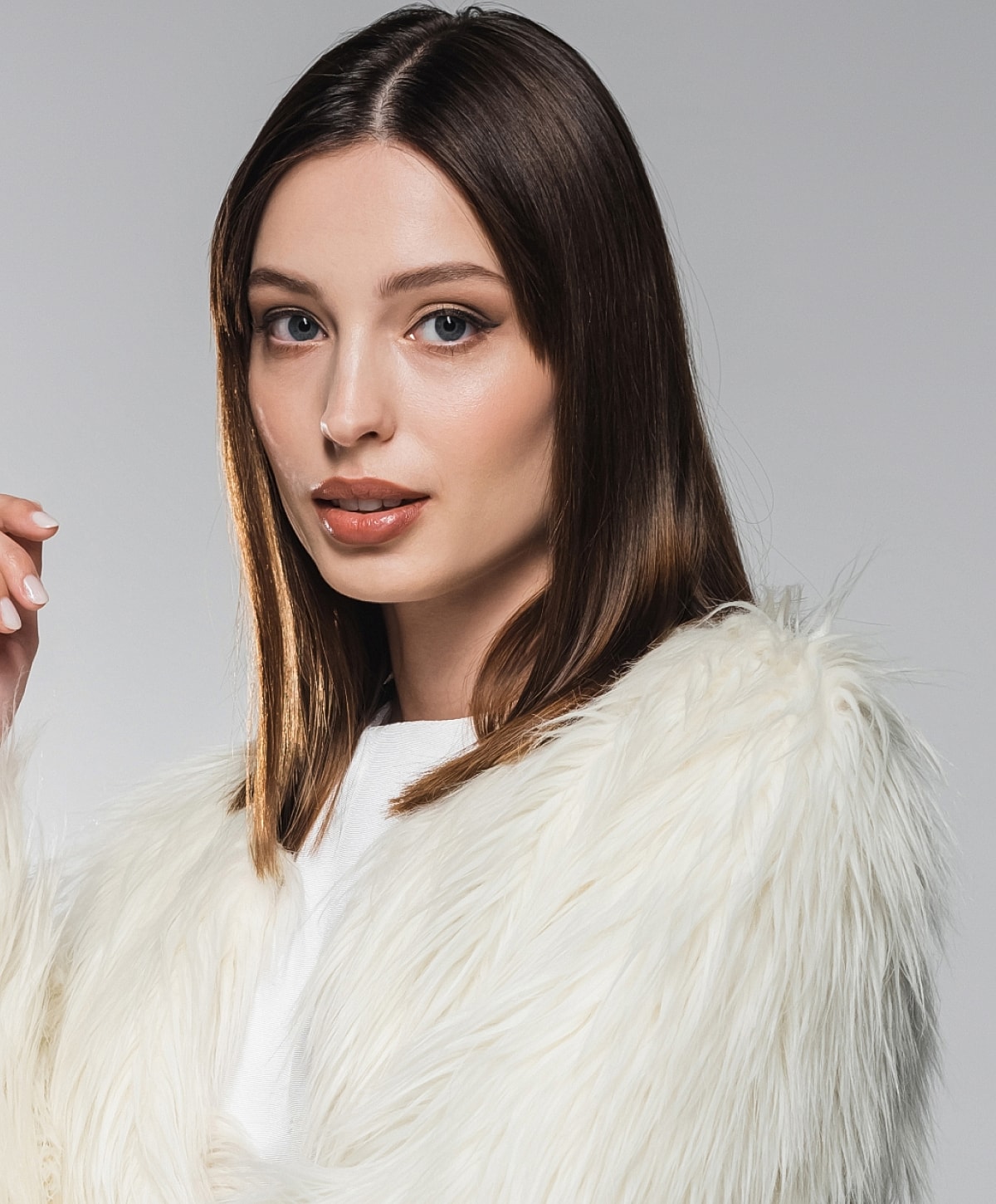 Woman wearing a stylish white fur coat.